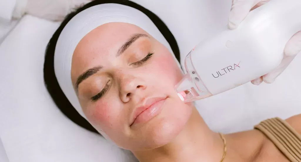 Woman receiving facial skin treatment with a handheld device, in a medical setting.