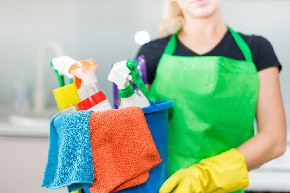 Person In Apron Holding A Cleaning Caddy With Spray Bottles — RWM Cleaning in Deception Bay, QLD