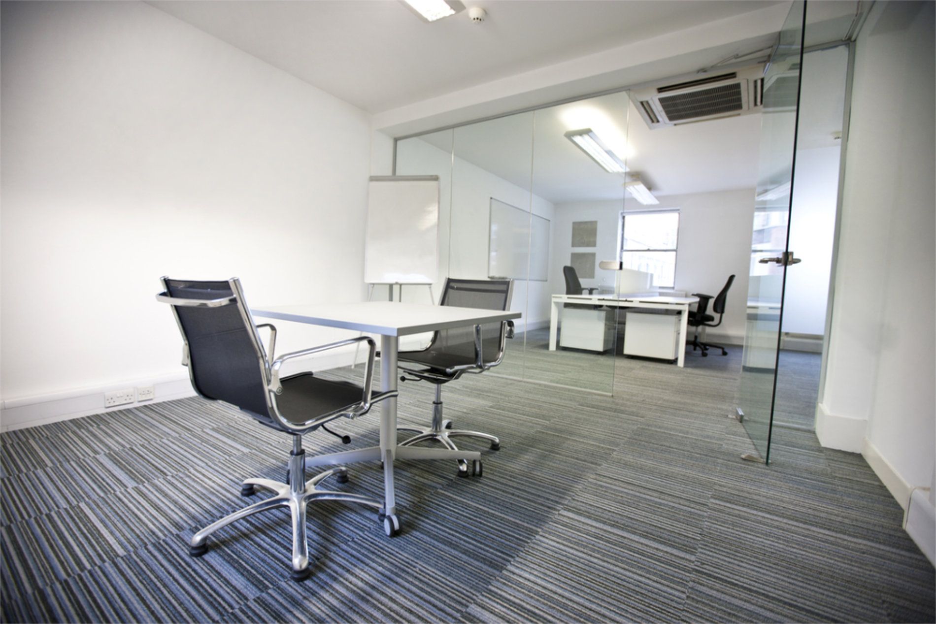 Office with meeting table and chairs, glass partition revealing desks and window — RWM Cleaning in Deception Bay, QLD