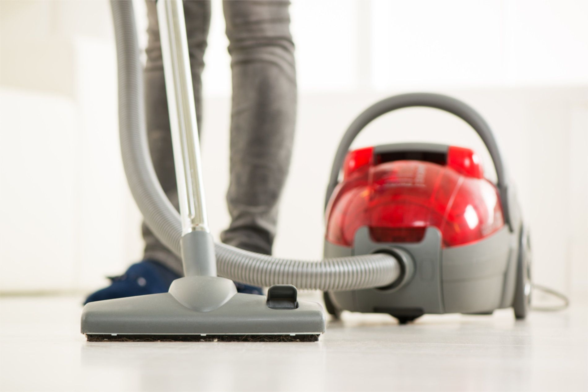 Person vacuuming with a red and gray vacuum cleaner on a white floor — RWM Cleaning in Aspley, QLD