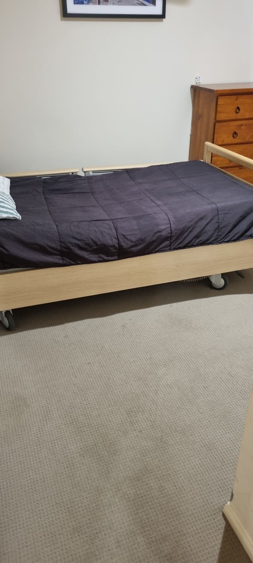 Bed With Dark Comforter on Wheels in a Room With Light Carpet — RWM Cleaning in Deception Bay, QLD