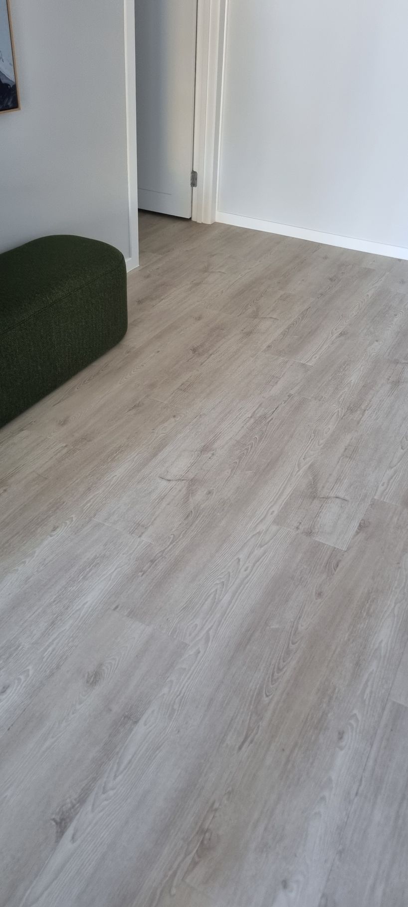 A Room With Light-colored Wood-look Flooring and a Dark Green Ottoman — RWM Cleaning in Deception Bay, QLD