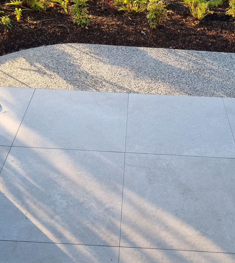 Light gray stone patio with a gravel border leading to a garden bed with green plants — RWM Cleaning in Deception Bay, QLD