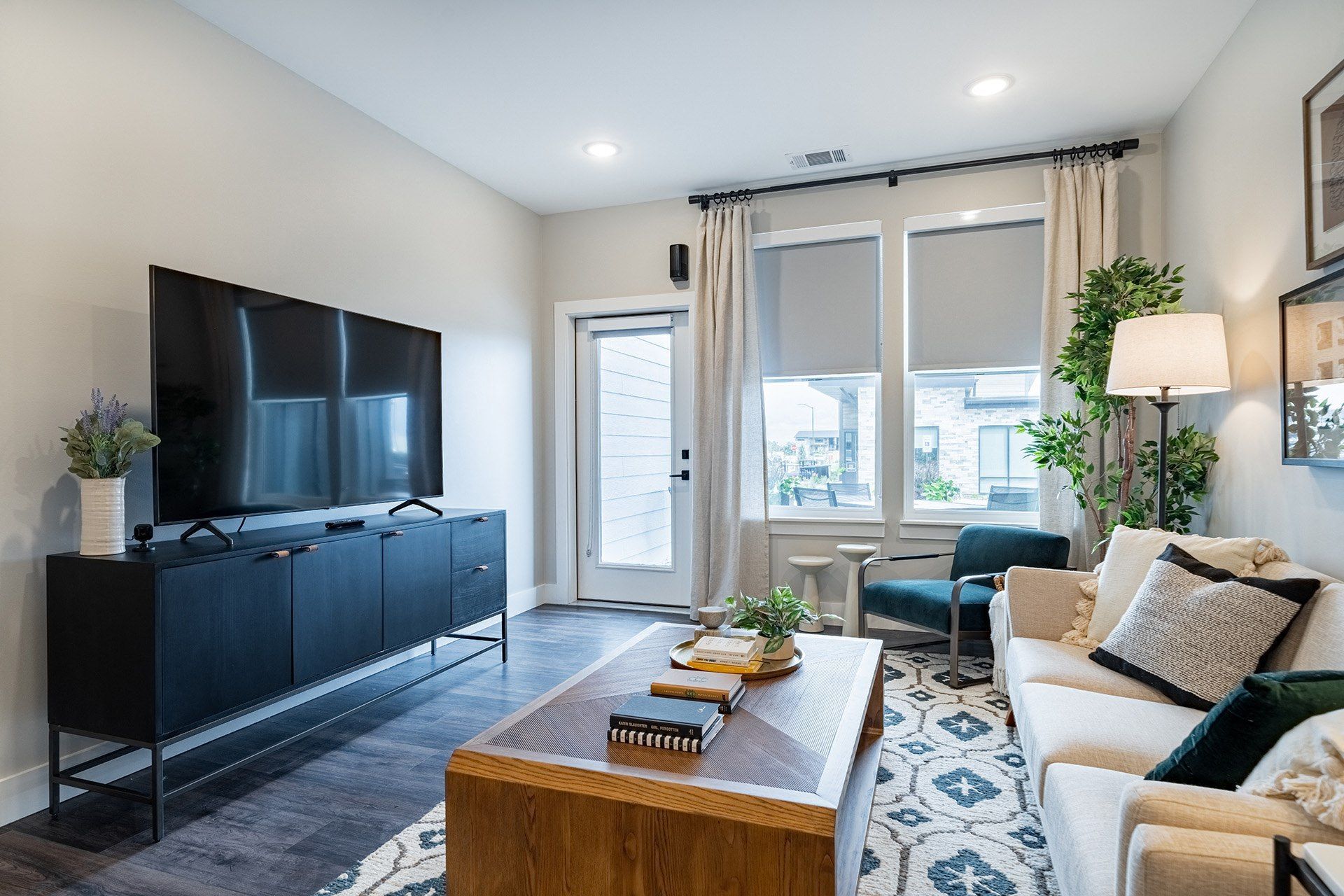 19th and Graf  Apartments Living room with TV, black cabinet, sofa, rug, and window with blinds.