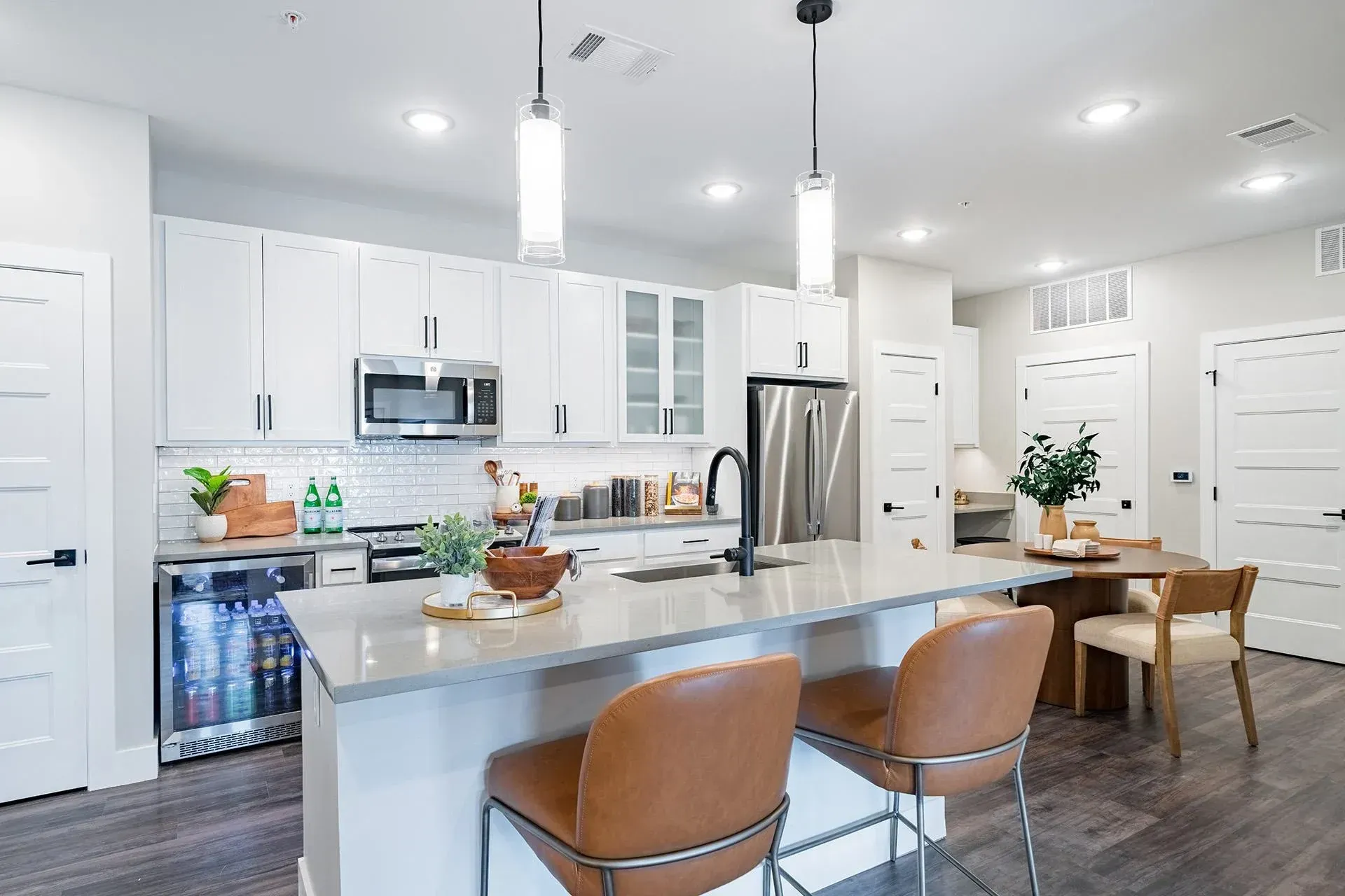 19th and Graf  Apartments Modern kitchen with white cabinets, stainless steel appliances, and a gray island with bar stools.