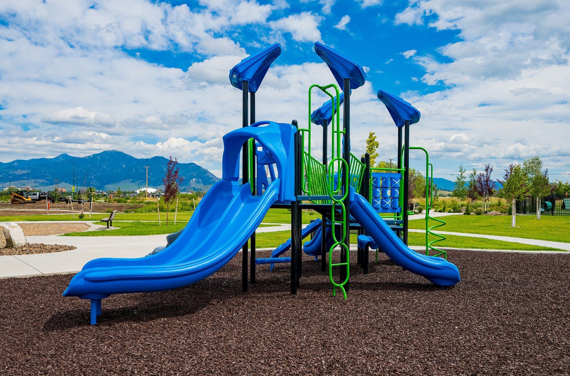 19th and Graf  Apartments Blue and green playground slide with ladders in a park setting.