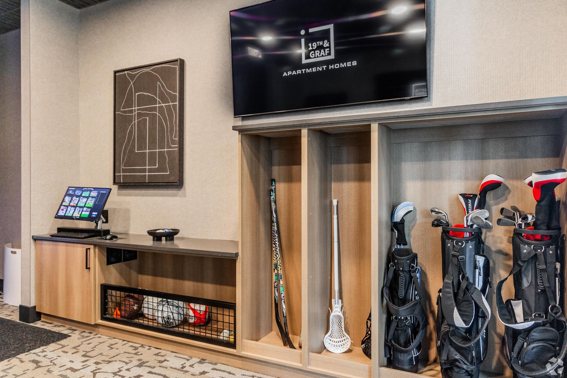 19th and Graf  Apartments Golf club storage area with mounted TV, artwork, and a computer setup.