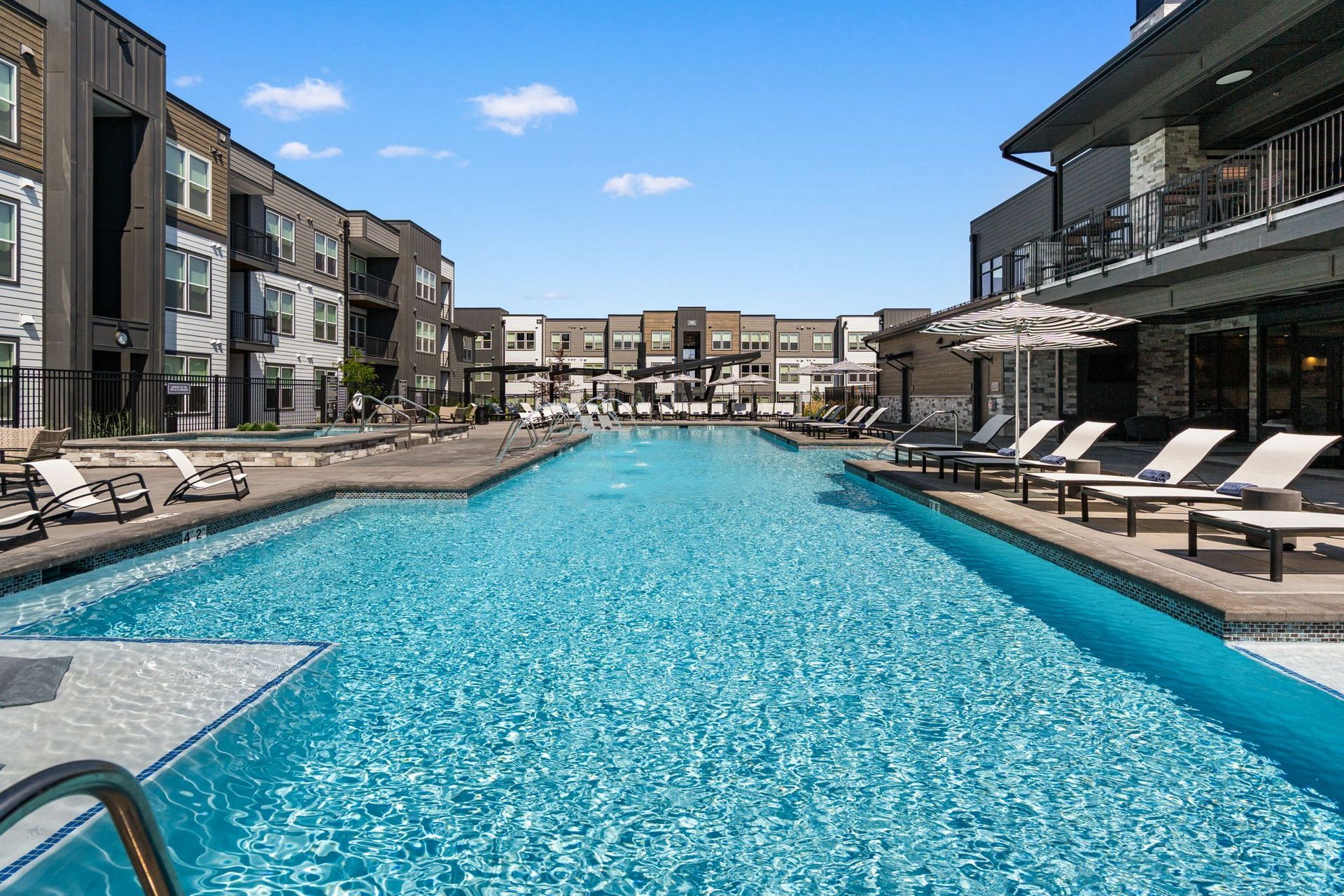 19th and Graf  Apartments Swimming pool flanked by apartment buildings with lounge chairs. Sunny day, blue water.