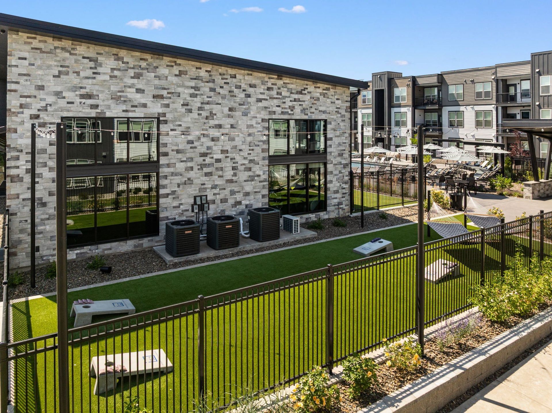 19th and Graf  Apartments Exterior view of modern apartment building with fenced dog park and green artificial turf.