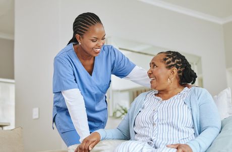 Man in a wheelchair smiling at a child in a bright room, with exercise equipment in the background