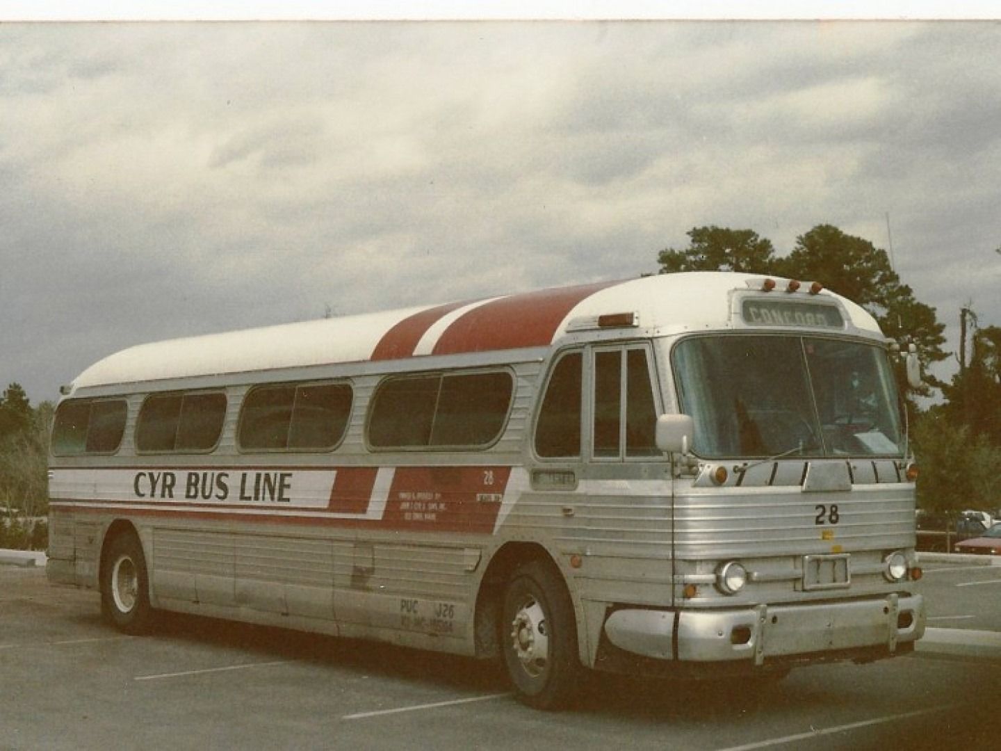 Vintage silver and red CYR BUS LINE coach bus parked outdoors under a cloudy sky