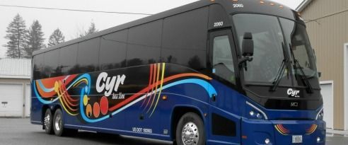 Blue and black charter bus with colorful swirl graphics parked outdoors