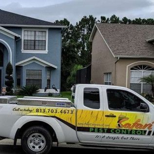 White Safari Pest Control truck parked in front of two houses. Truck has yellow and brown tiger print.