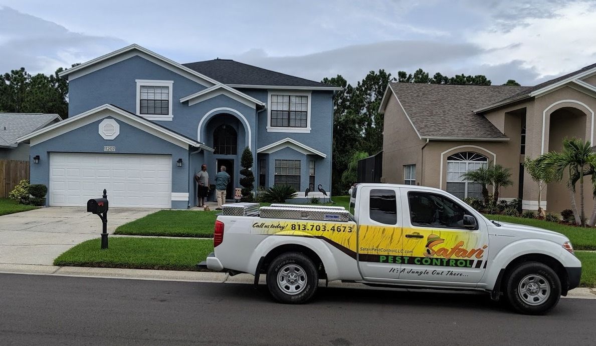 White truck parked in front of a blue house; other houses visible. Truck has business logo. Overcast day.