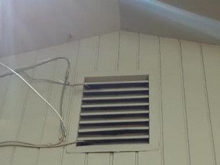 Exterior wall with a rectangular vent and horizontal slats.