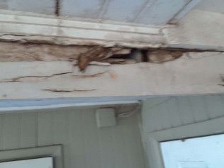 Damaged white painted wooden beam with dark discoloration.