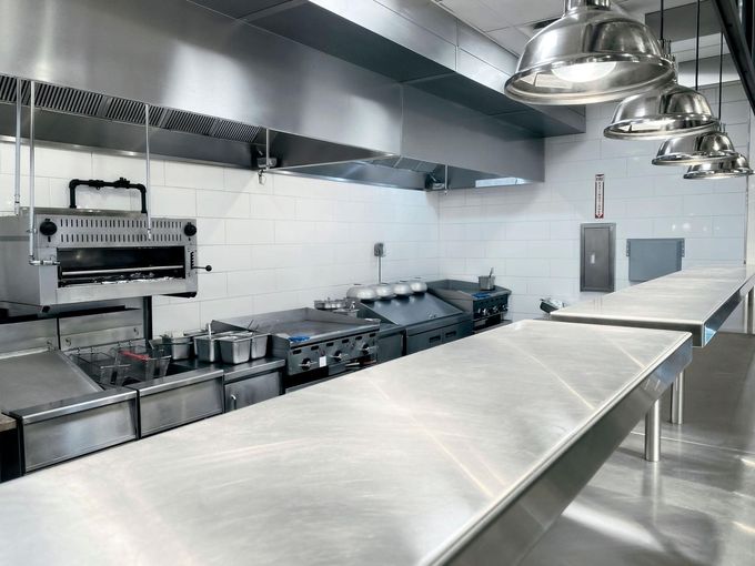 Worker cleaning a restaurant kitchen floor with a mop and bucket