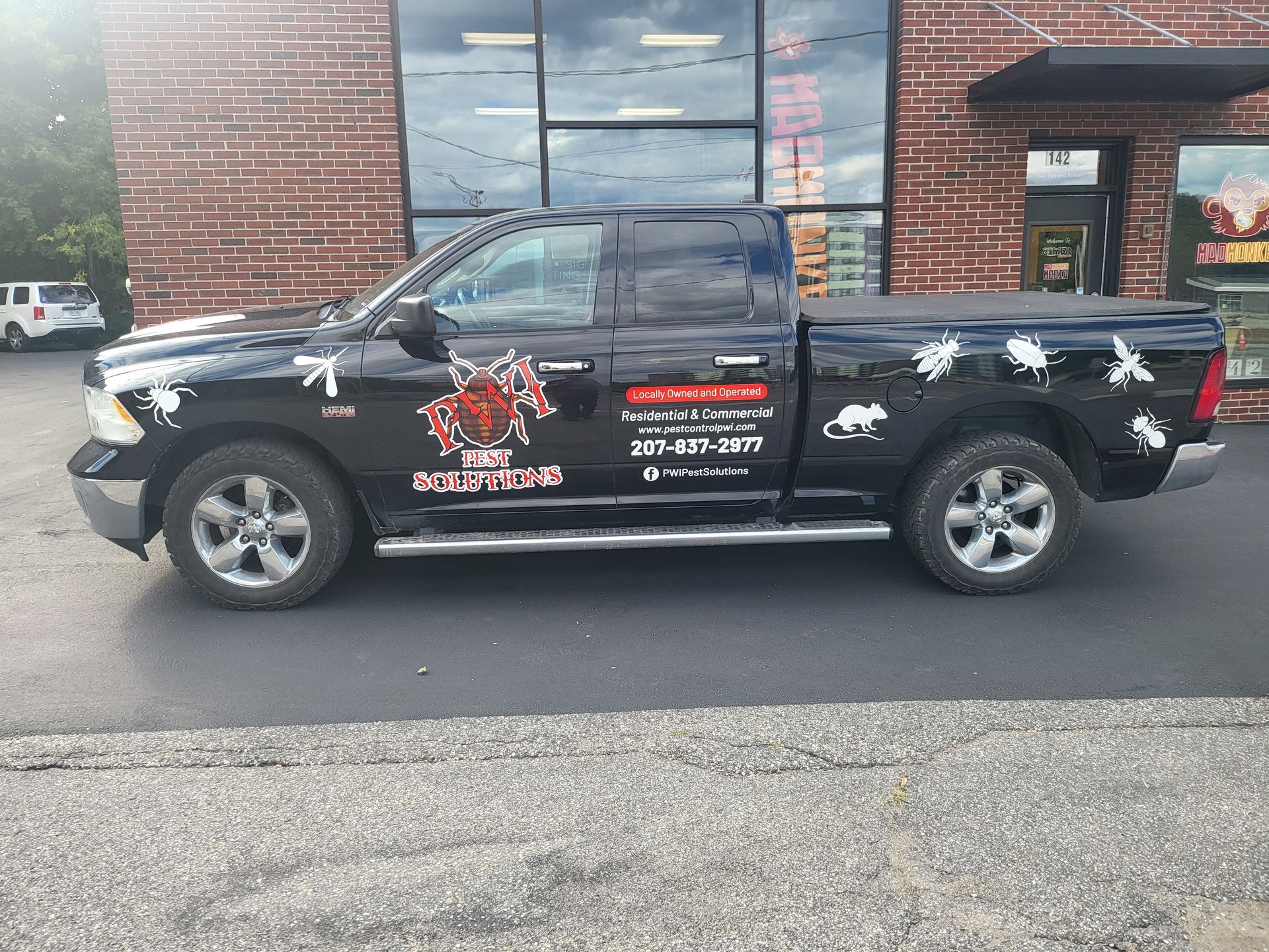 Black pickup truck with company decals parked outside a brick storefront
