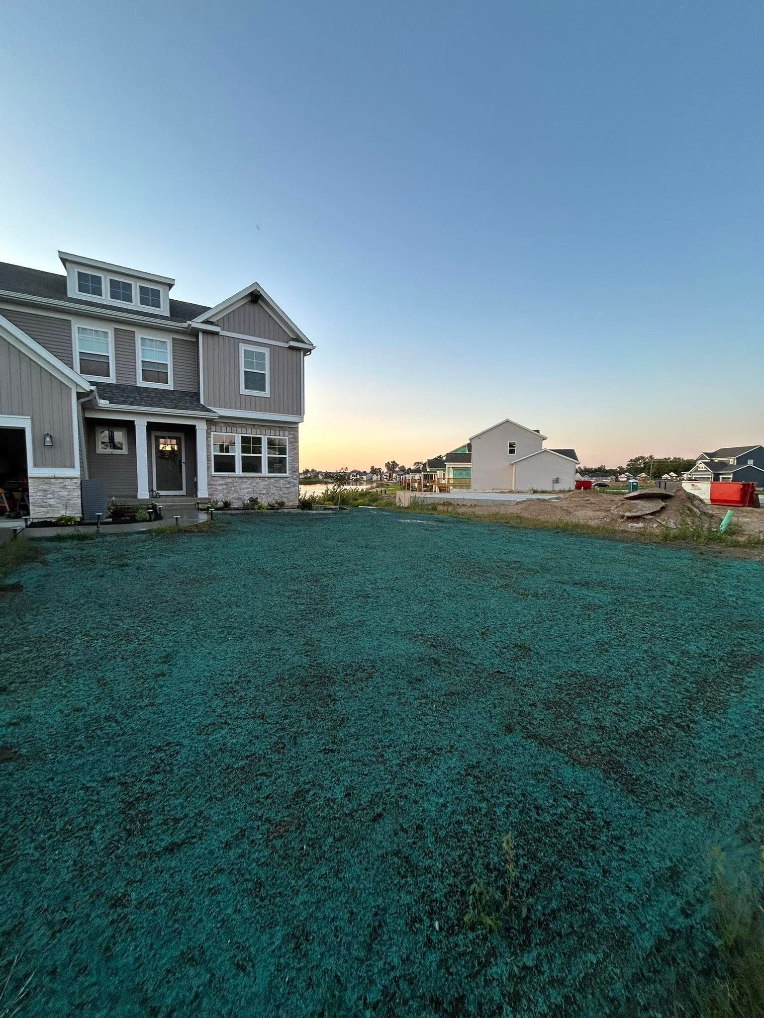 Suburban house with teal lawn and sunset sky, viewed from a front yard