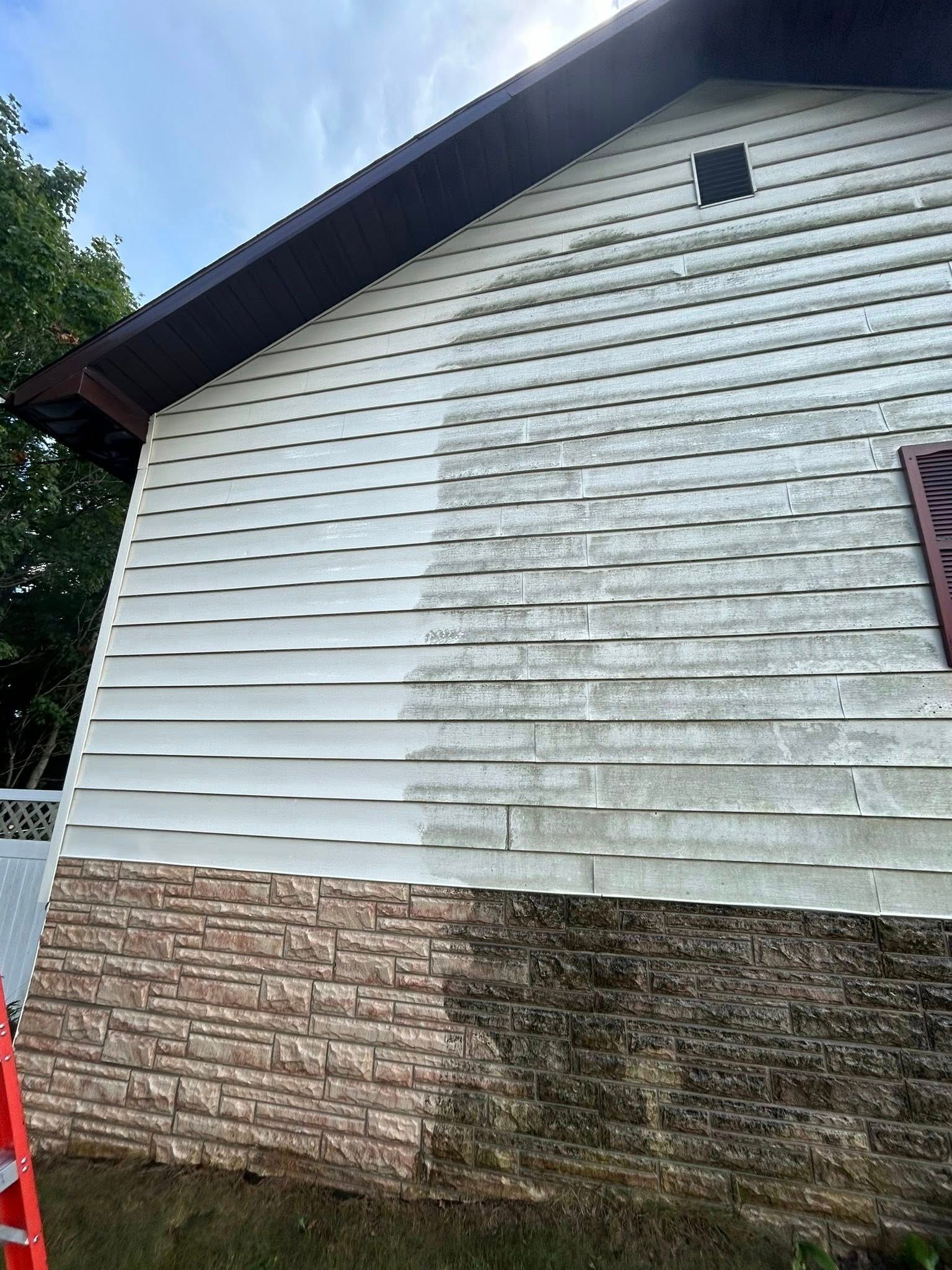 White house siding with heavy gray mildew stains above a brick foundation under a dark roofline
