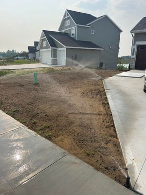 New suburban house with unfinished dirt front yard and wet concrete driveway/sidewalk