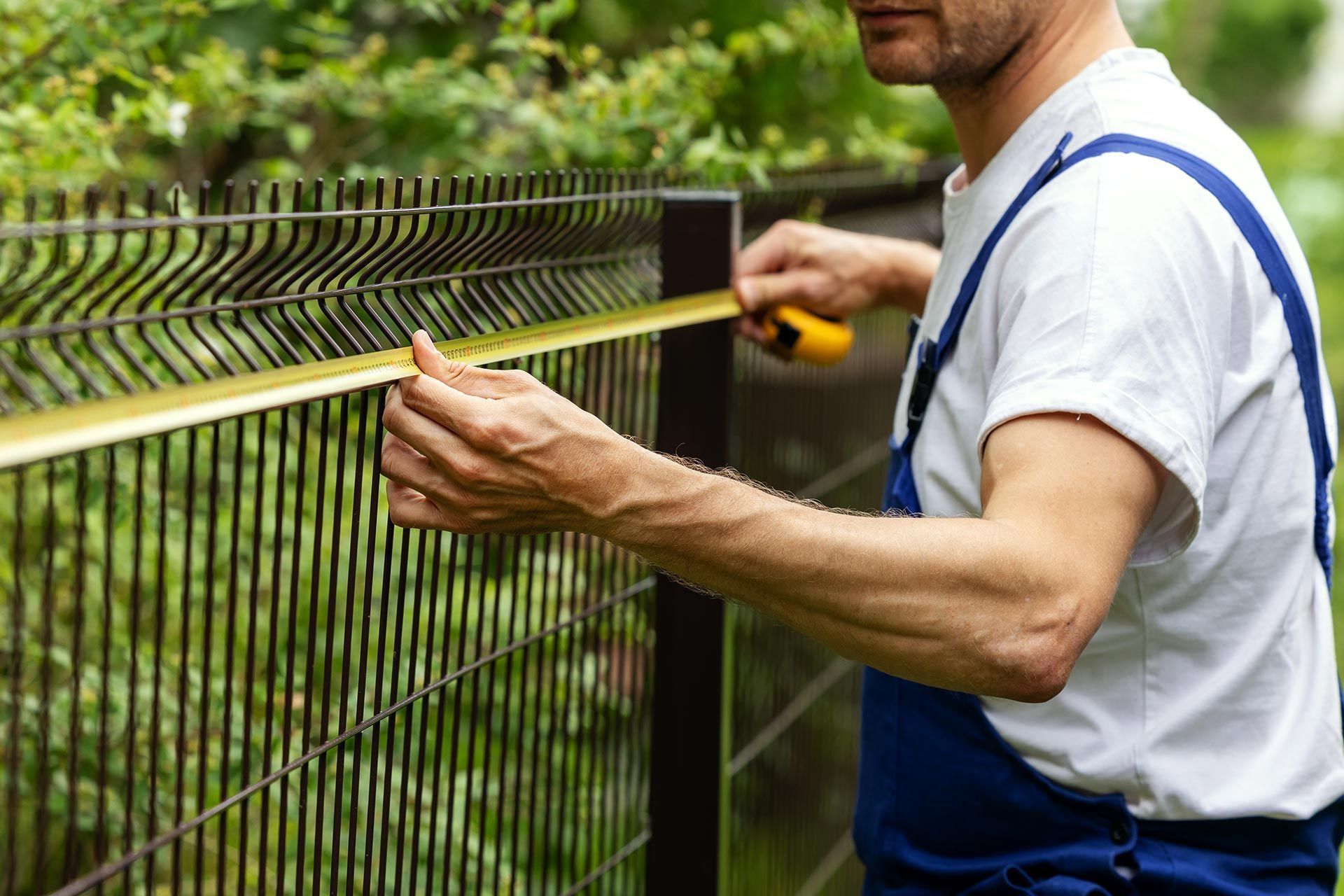 worker taking measurements with measuring tape for new fence. worker taking measurements with measuring tape for new fence.