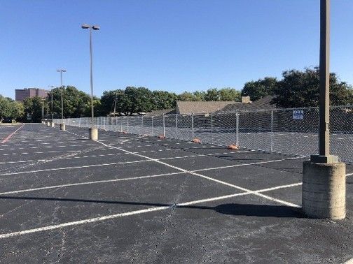 Temporary chain link fence rental installed around a commercial parking lot for site security and access control. Temporary chain link fence rental installed around a commercial parking lot for site security and access control.