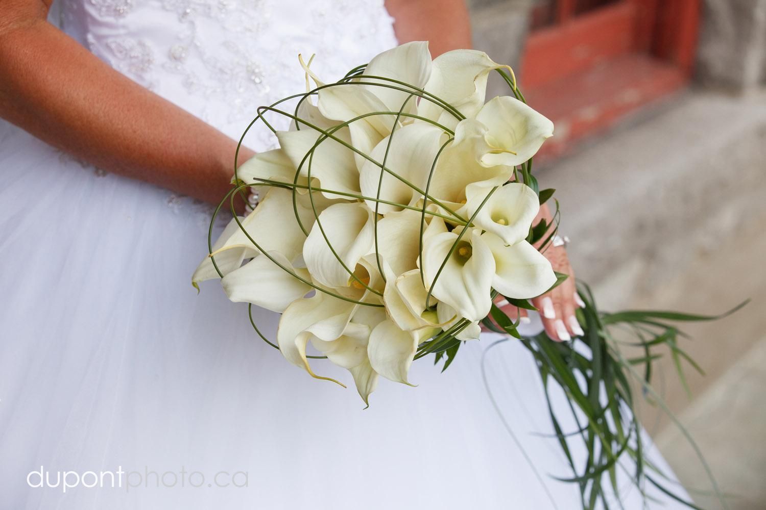 Une mariée en robe blanche tient un bouquet de fleurs blanches