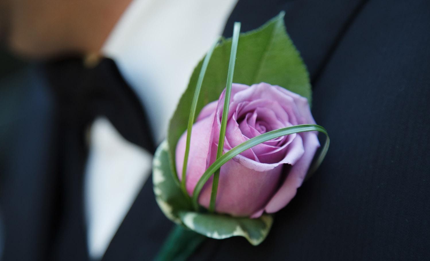 Un gros plan d'une rose violette sur la veste d'un homme