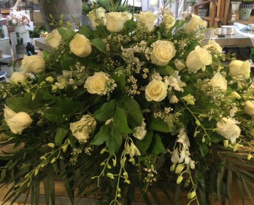 Un grand bouquet de roses blanches et de verdure est posé sur une table.