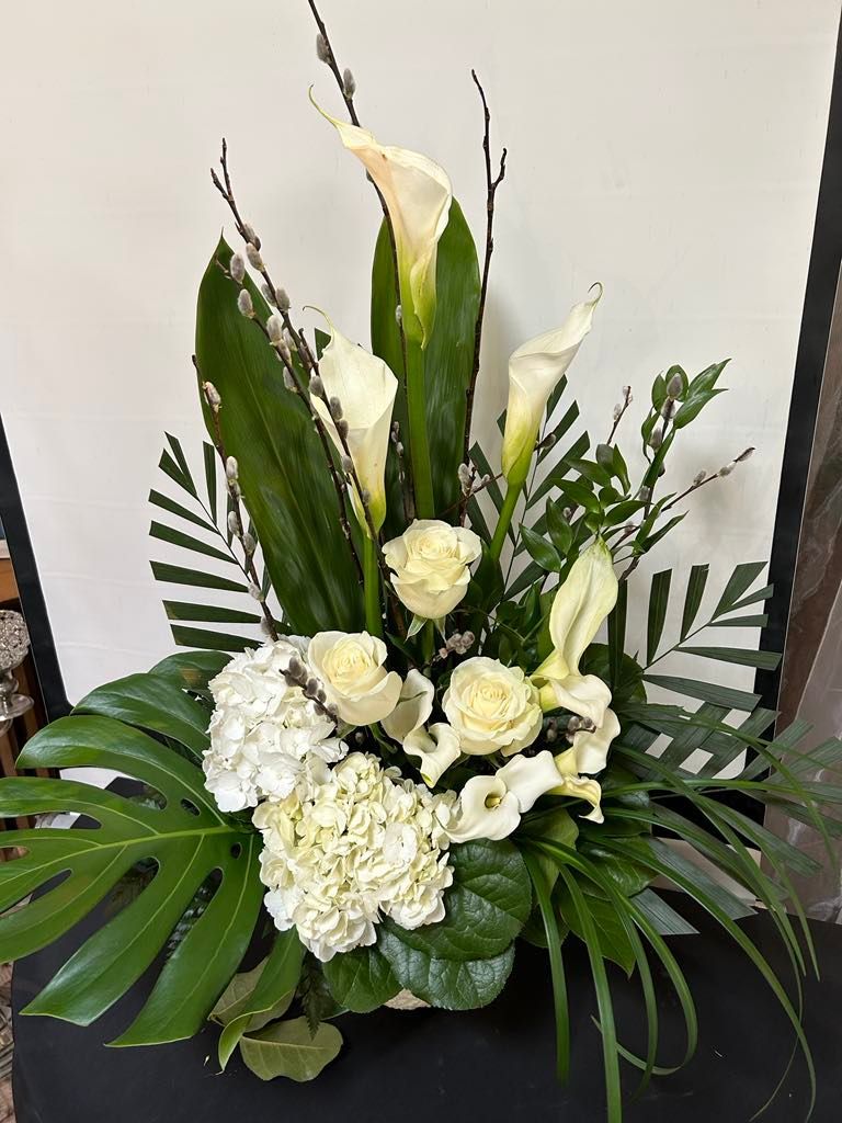 Un bouquet de fleurs blanches et de feuilles vertes est posé sur une table.