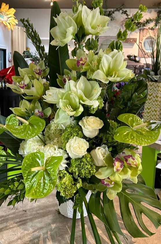 Un vase rempli de fleurs blanches et de feuilles vertes est posé sur une table.