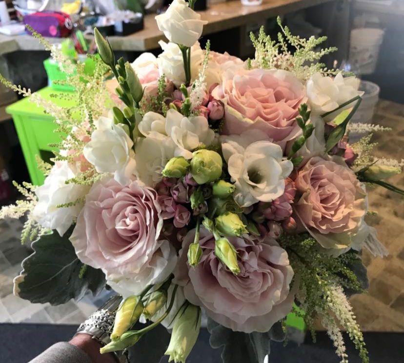 Une personne tient un bouquet de fleurs roses et blanches