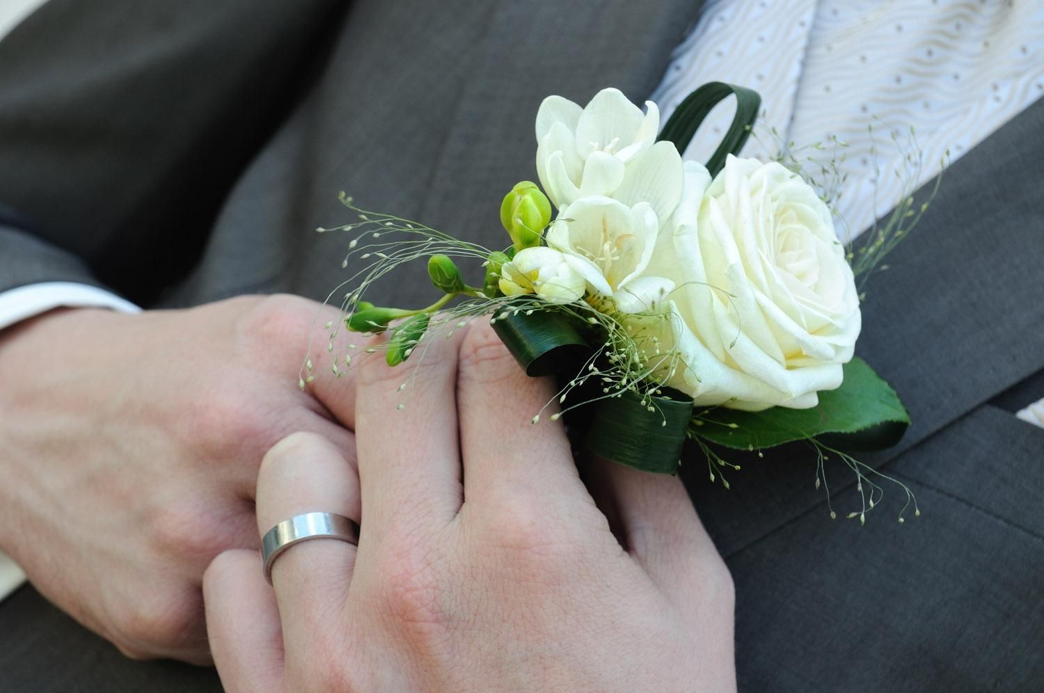 Un homme portant une alliance tient une rose blanche