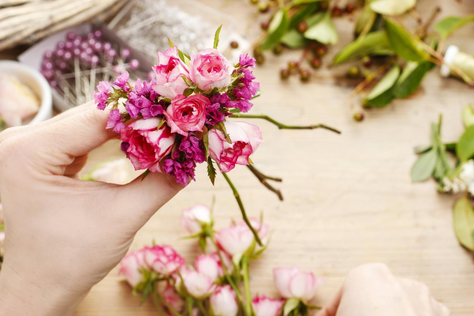 Une personne tient un bouquet de fleurs roses dans sa main.