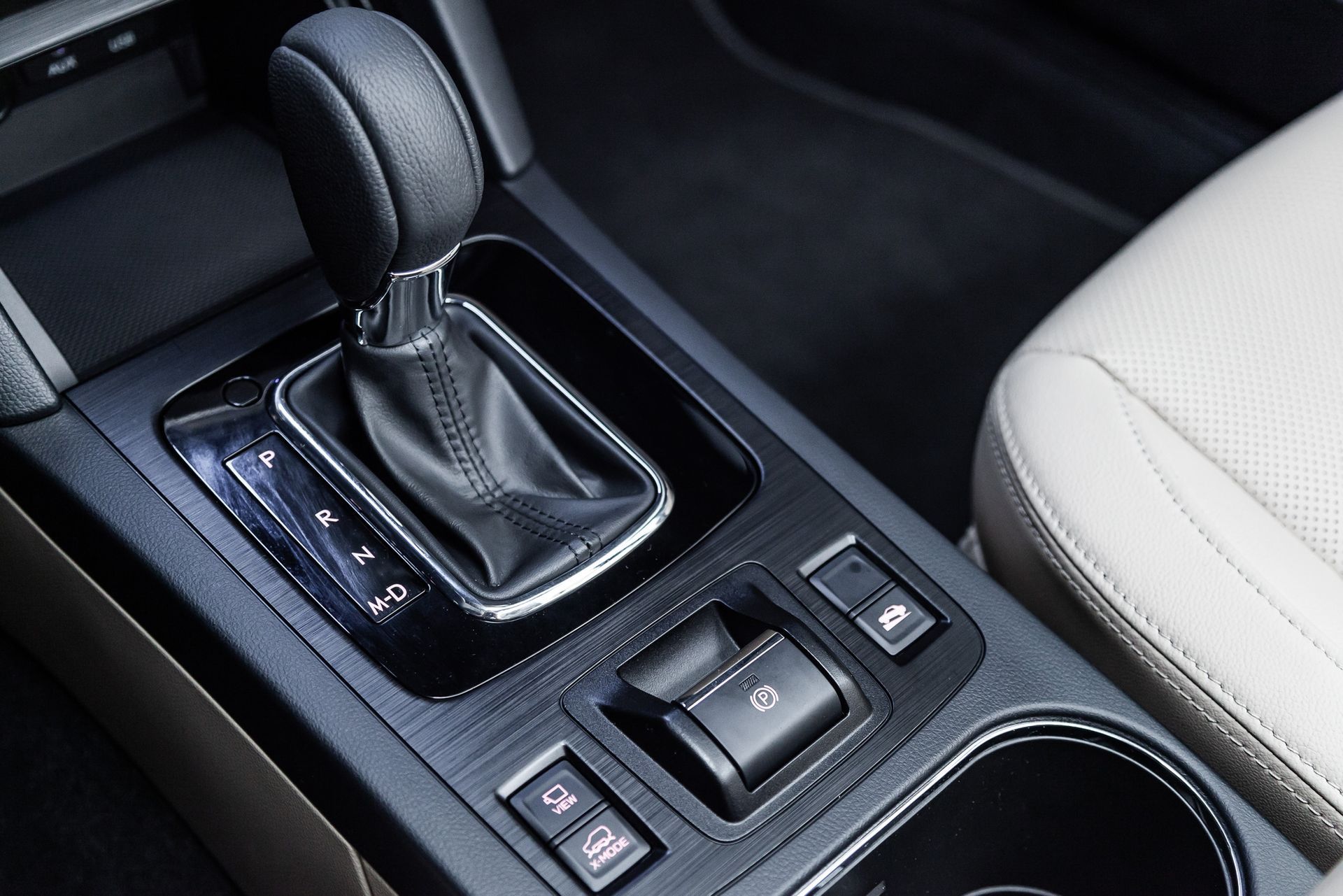 Close-up of a car's center console featuring a black gear shift, parking brake, and various buttons.