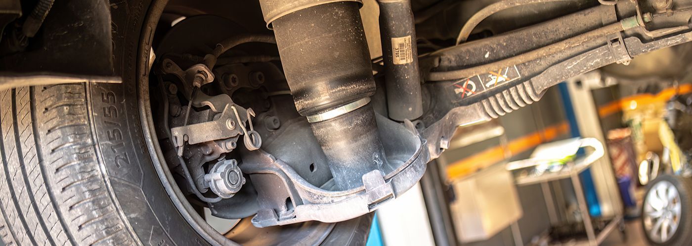 Undercarriage of a vehicle, showing suspension components, including a shock absorber and brake caliper.
