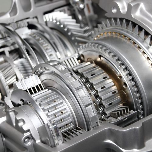 Close-up of a silver automobile transmission, revealing gears, chains, and mechanical components.