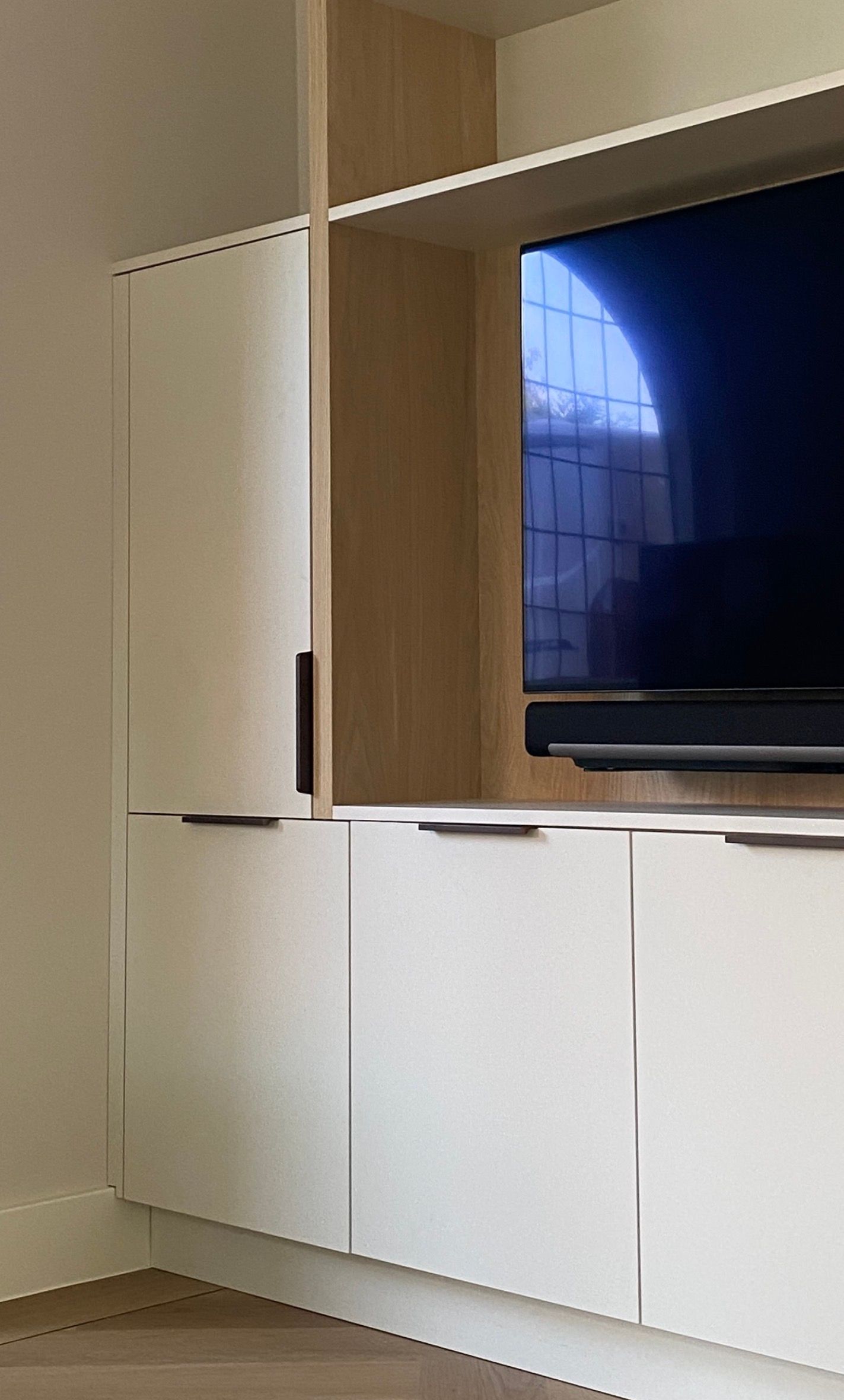 Minimalistisch licht tv-meubel met houten accenten en een flatscreen-tv in een moderne kamer | Villa18 Interieurdesign