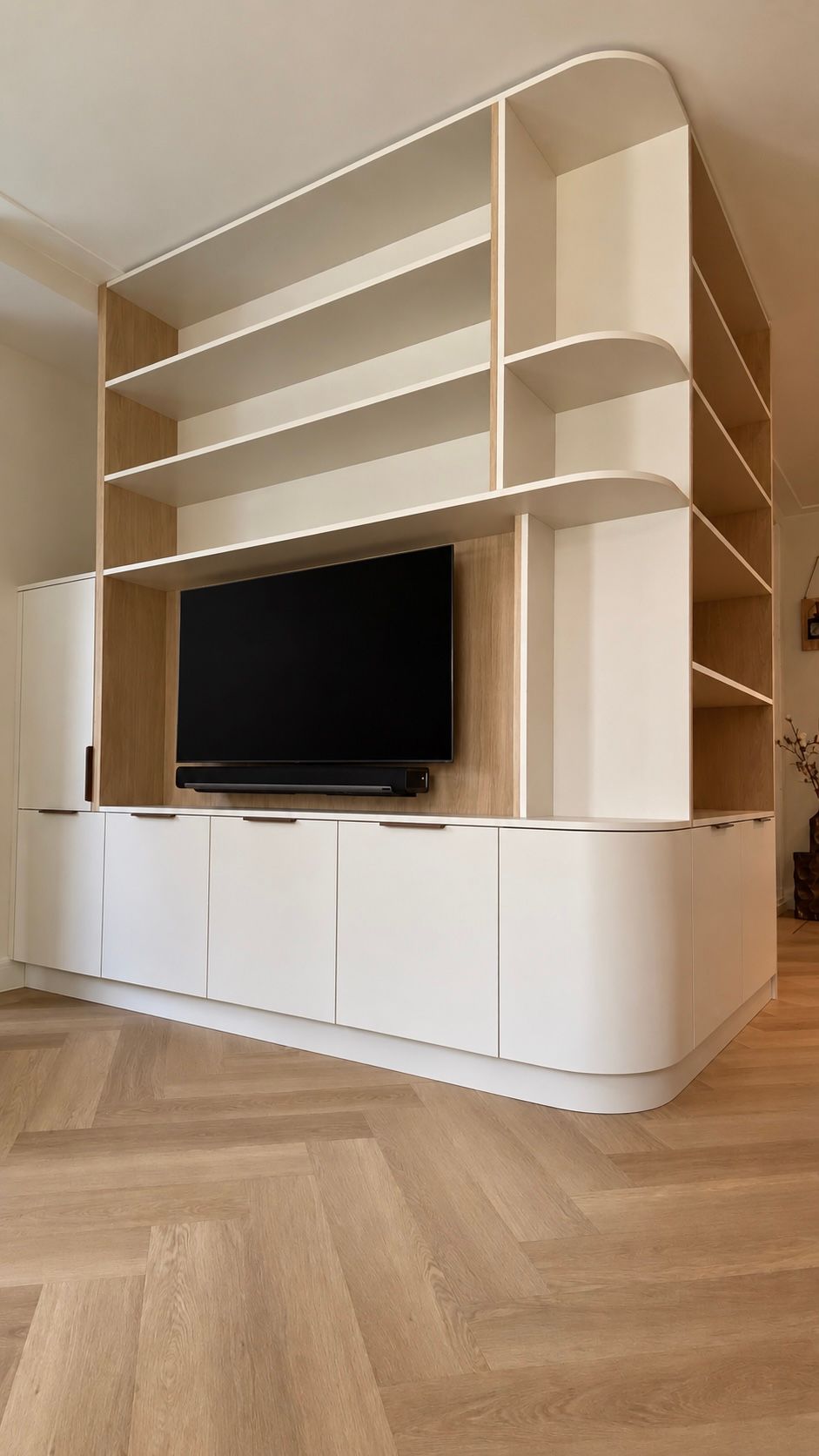 Ingebouwde maatwerk wandkast met lichte kasten, open vakken en een tv in een woonkamer met een lichte houten vloer | Villa18