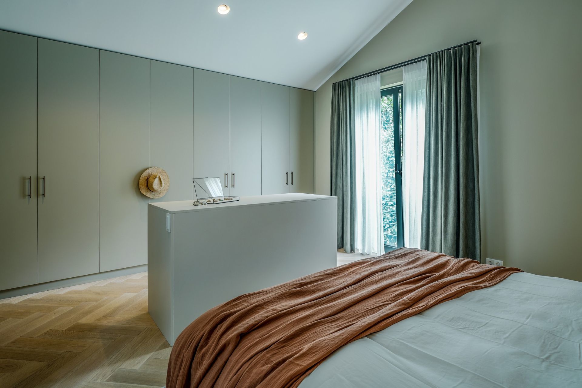 Master bedroom in jaren 70 villa met warme natuurlijke kleuren en maatwerk kledingkast en eiland | Villa18