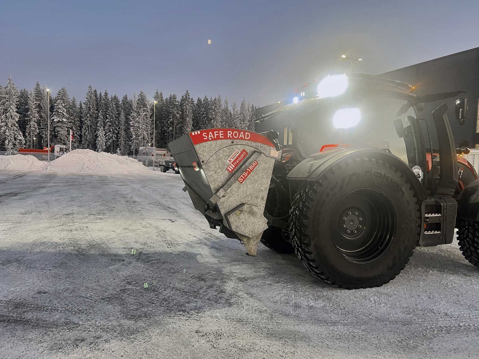 Traktor med lyset tændt kører med spreder