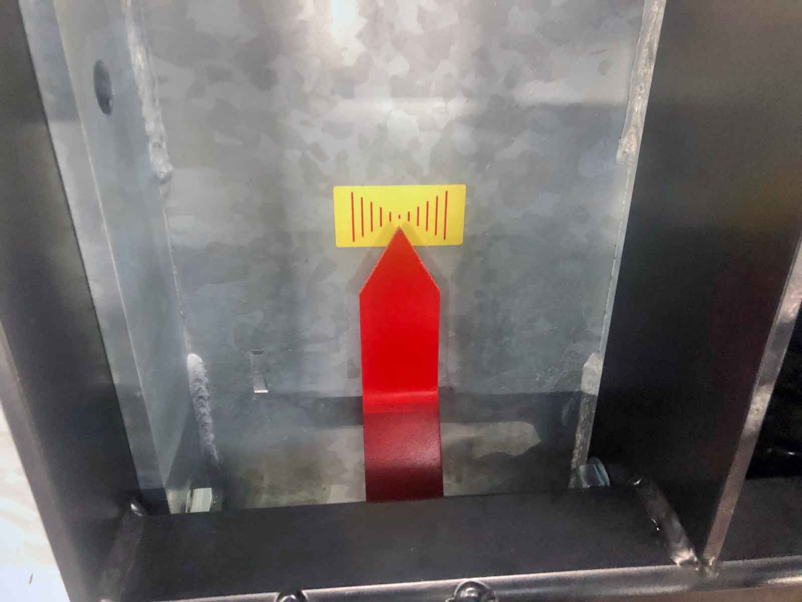 En rød pil der peger opad mod gul indikator på en metaltank.