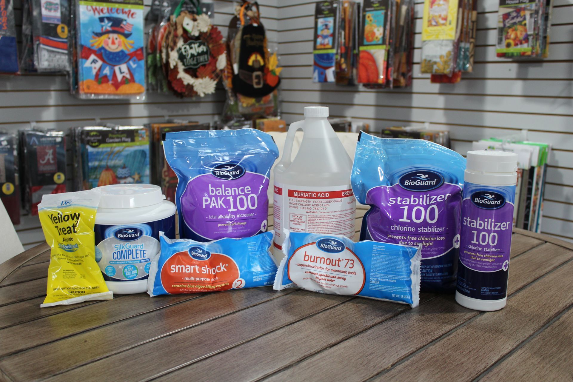 Assorted colorful cleaning and laundry products displayed on a wooden deck with hanging items in the background