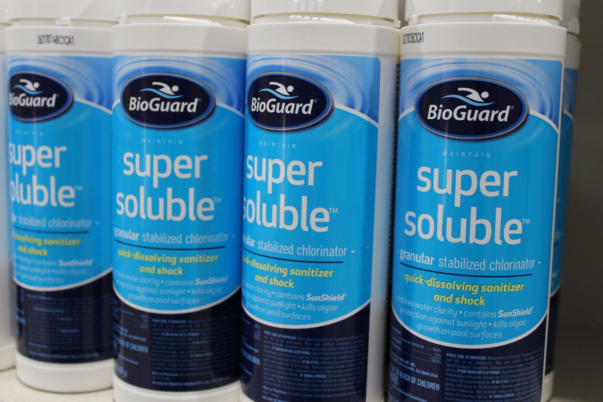 Four BioGuard Super Soluble product canisters with blue labels lined up on a shelf