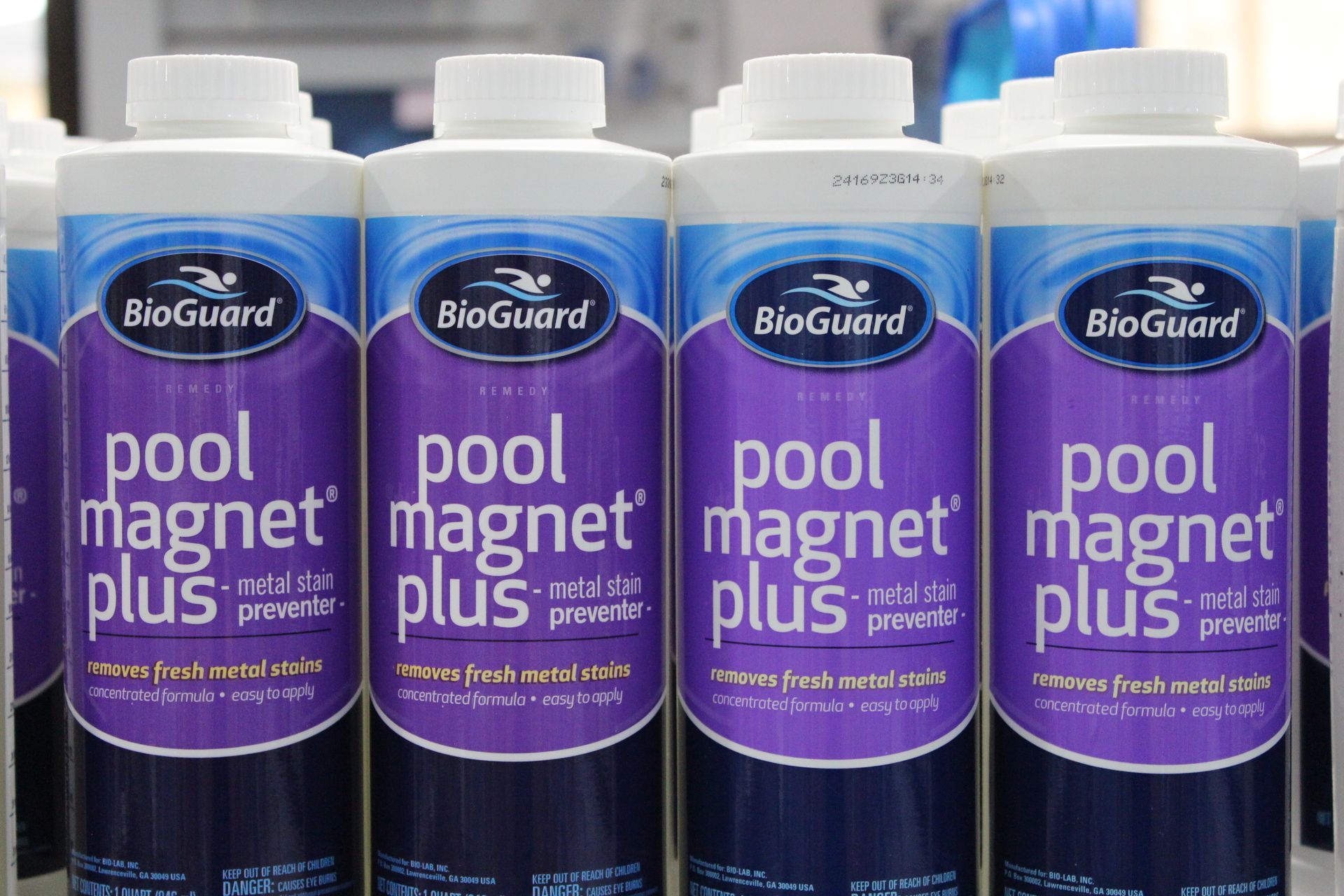 Four purple BioGuard Pool Magnet Plus bottles lined up on a store shelf.