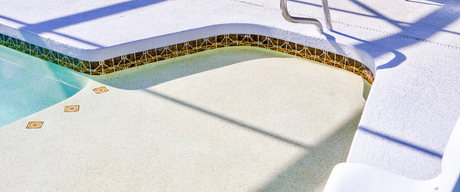 Snow-covered outdoor pool with a curved blue edge and a thin line of debris along the rim