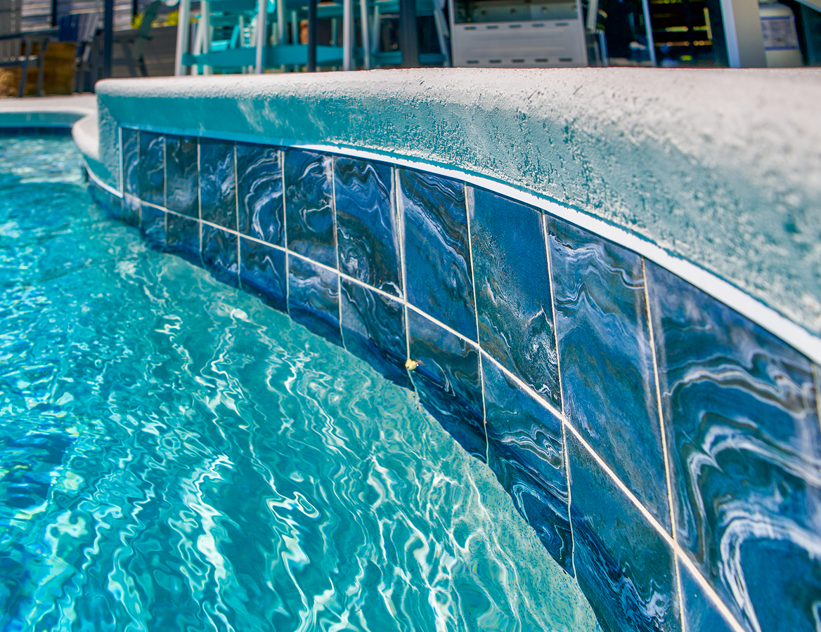 Curved blue-tiled pool edge with rippling turquoise water