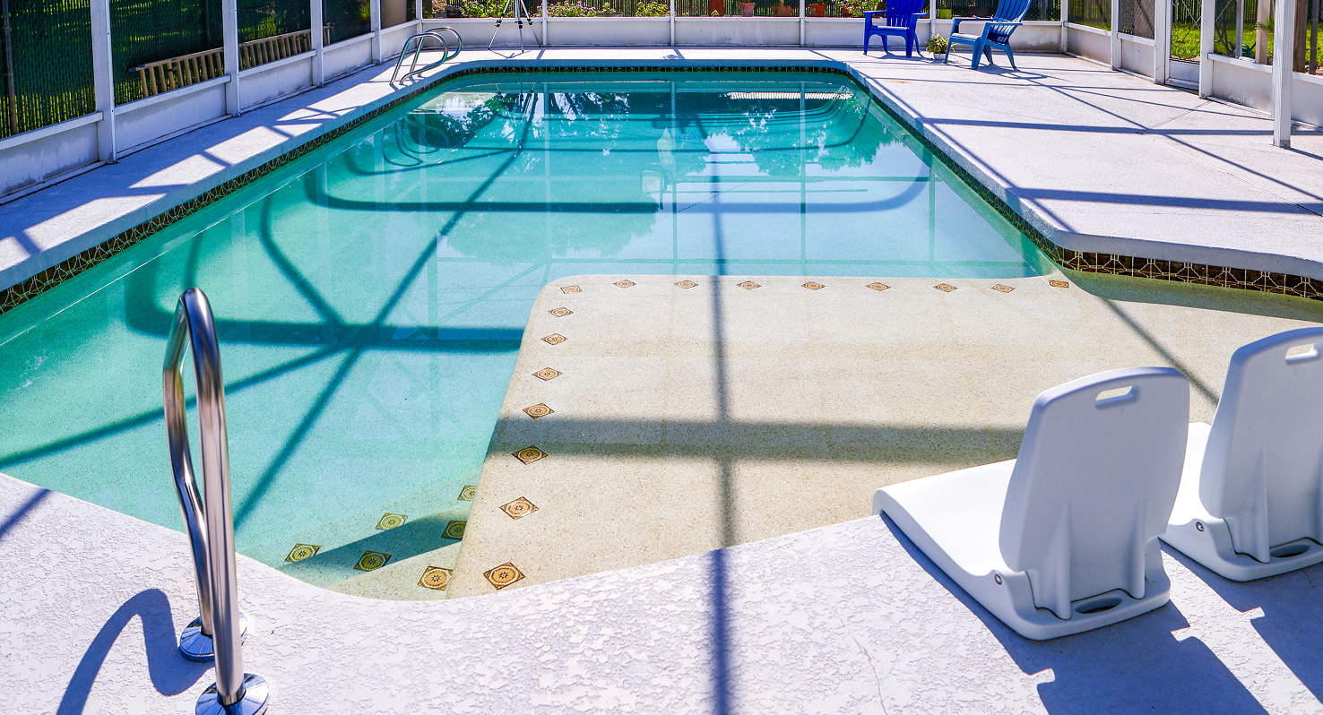 Outdoor swimming pool with turquoise water and white lounge chairs under a covered deck