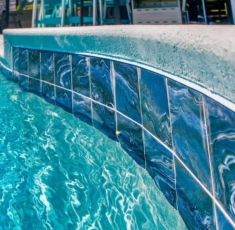 Curved pool wall with blue tile and rippling turquoise water